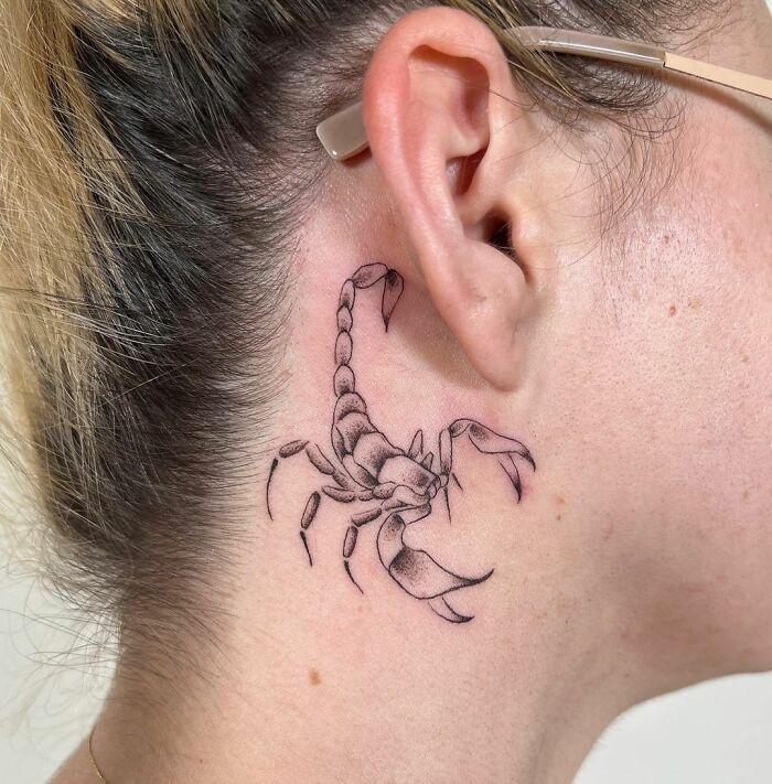 Scorpion zodiac tattoo behind ear, detailed and striking design.
