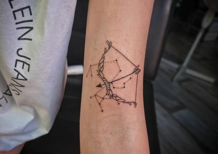 Sagittarius zodiac tattoo featuring a constellation and bow design on a person's forearm.