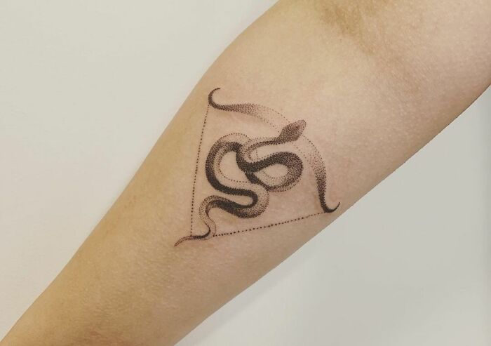 Snake zodiac tattoo with geometric design on forearm.