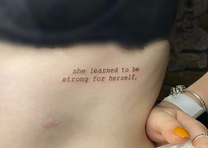 "She Learned To Be Strong For Herself" phrase tattoo 