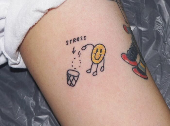 Happy smile throwing stress in a trash can arm tattoo