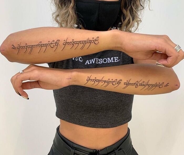 Person displaying elegant Lord of the Rings script tattoos on both forearms.