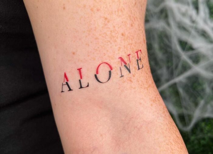 Red and black word "Alone" tattoo 