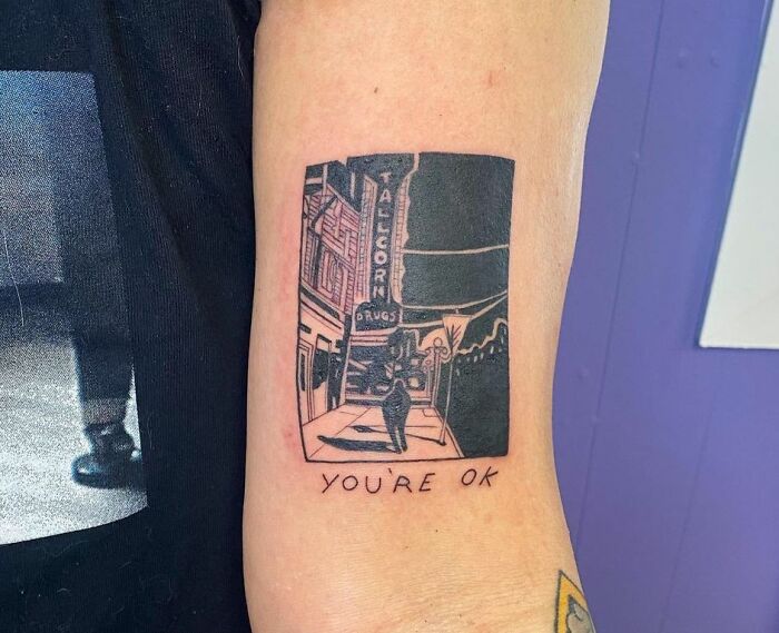 Street during night with man walking, "You're ok" inscription tattoo 