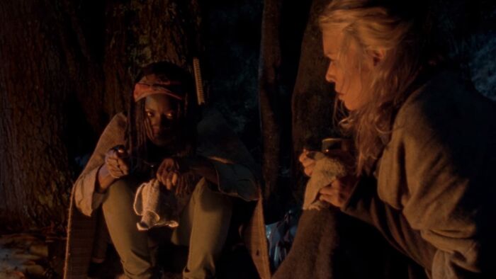Michonne sitting near a fire place 