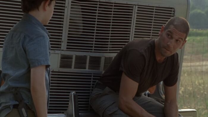 Shane Walsh sitting on a car part 