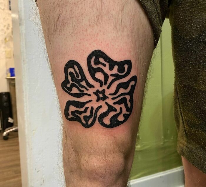 Black tribal tattoo design on a person's thigh.