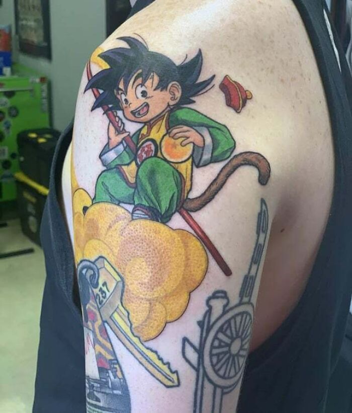 Goku on Nimbus with dragon ball wearing yellow and green clothes shoulder armTattoo