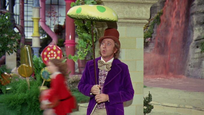 Willy Wonka standing under mushroom umbrella 