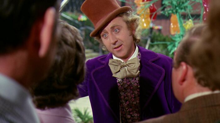 Willy Wonka telling something to his guests 