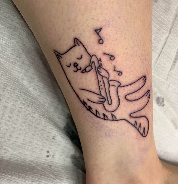 Cat playing with saxophone ankle tattoo