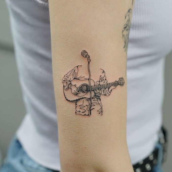 Tricep Tattoo with headless man playing guitar