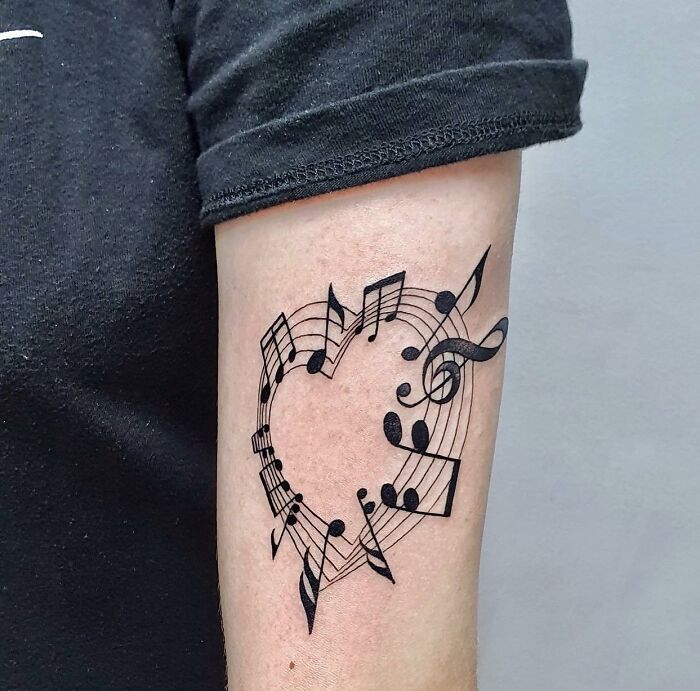 Black heart with music notes tattoo on arm