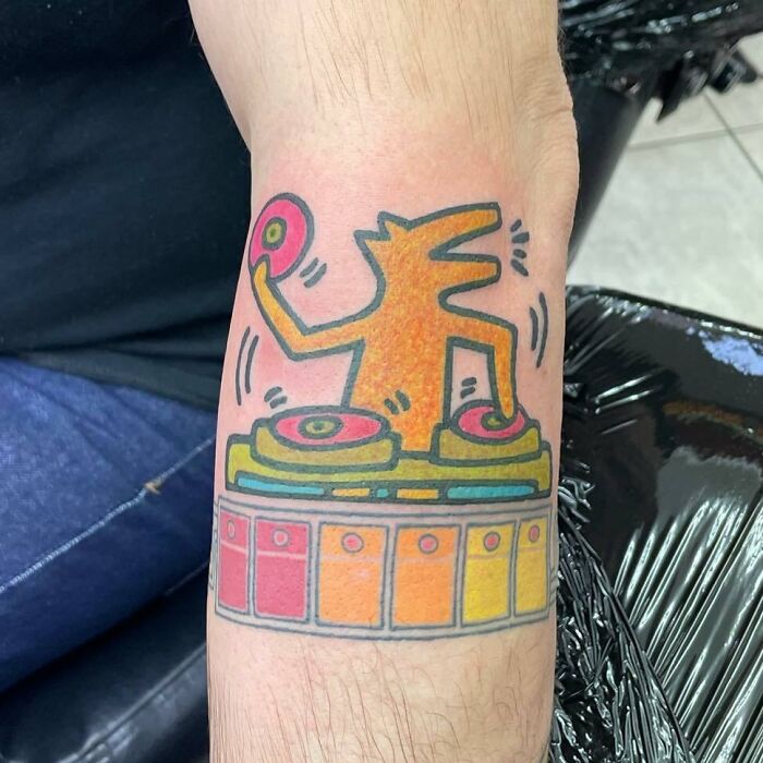 Colorful Keith Haring DJ dog tattoo on arm
