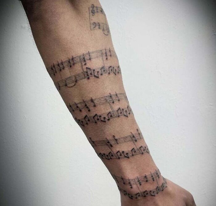 Music sheet wrapped around an arm tattoo