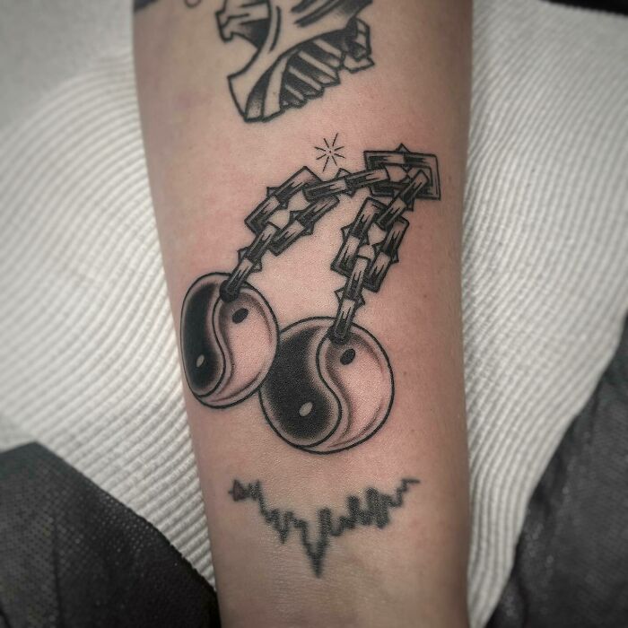 Two yin yang symbols handing on chains tattoo 
