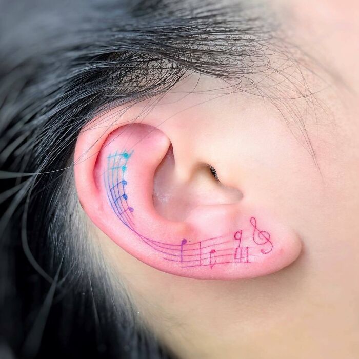 Colorful music notes on an ear tattoo