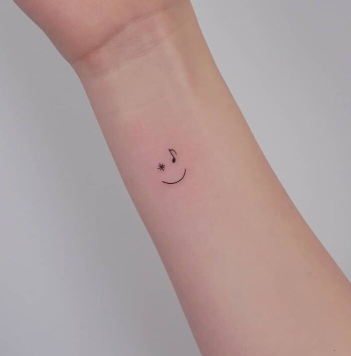 Minimal smile with music note wrist tattoo