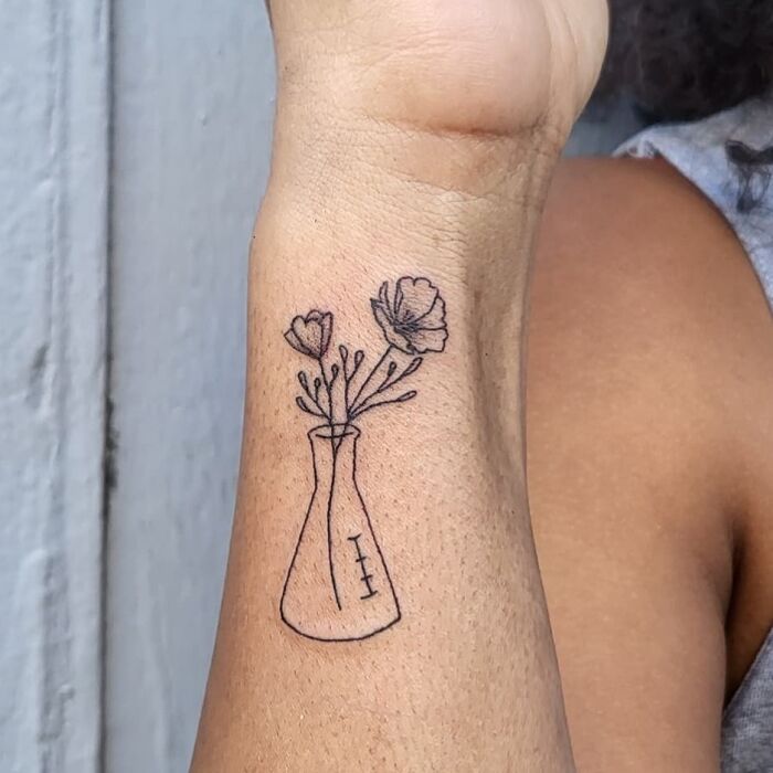Poppies in an Erlenmeyer flask tattoo on arm