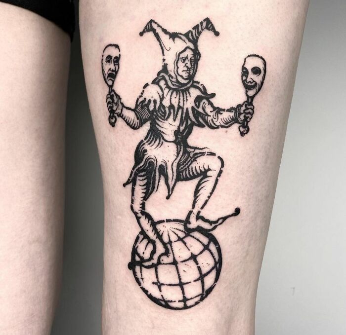 Gothic tattoo of a jester balancing on a globe, holding two masks.