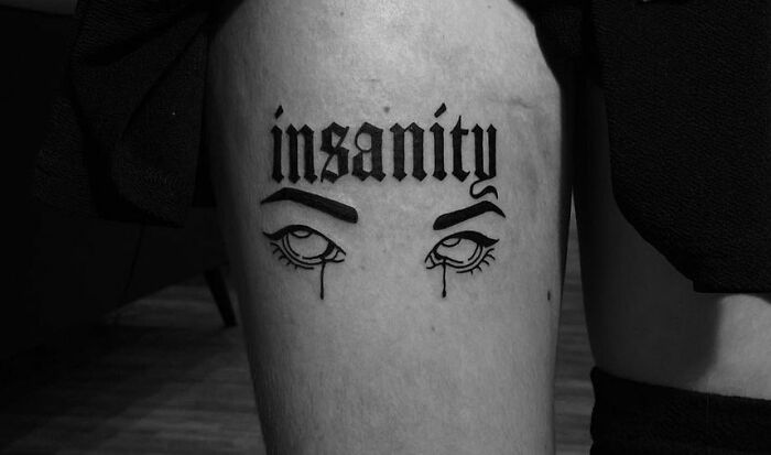 "Insanity" Written In A Gothic Font with rolling eyes under it Thigh Tattoo
