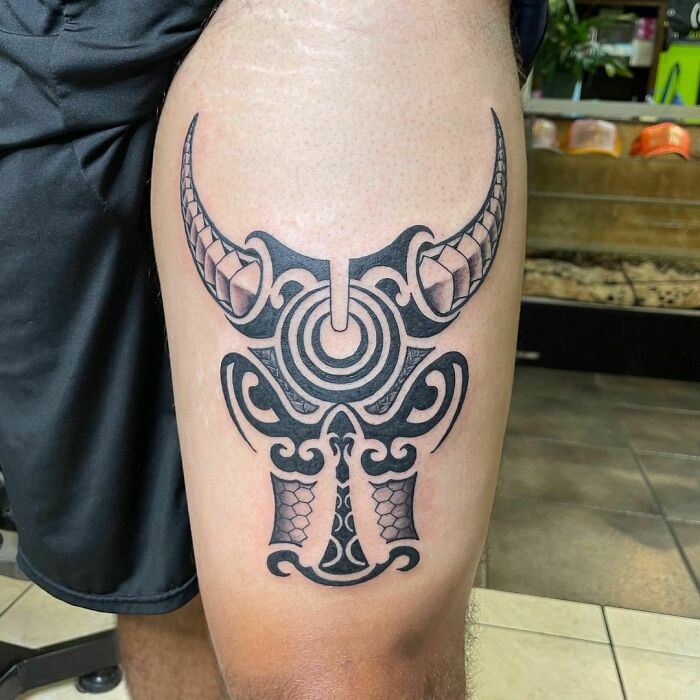 A tribal tattoo with intricate patterns and bold lines on a person's thigh.