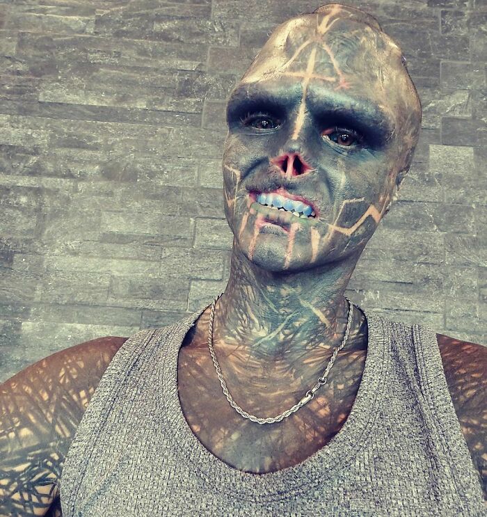 Tattooed individual with body modifications, wearing a tank top, facing daily judgement challenges. Tattooed individual with body modifications, wearing a tank top, facing daily judgement challenges.