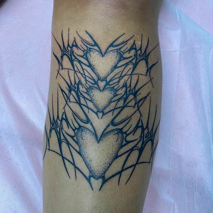 Detailed gothic tattoo with intricate heart and web patterns on a leg.