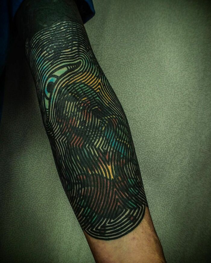 Colorful abstract gothic tattoo with intricate patterns on an arm.