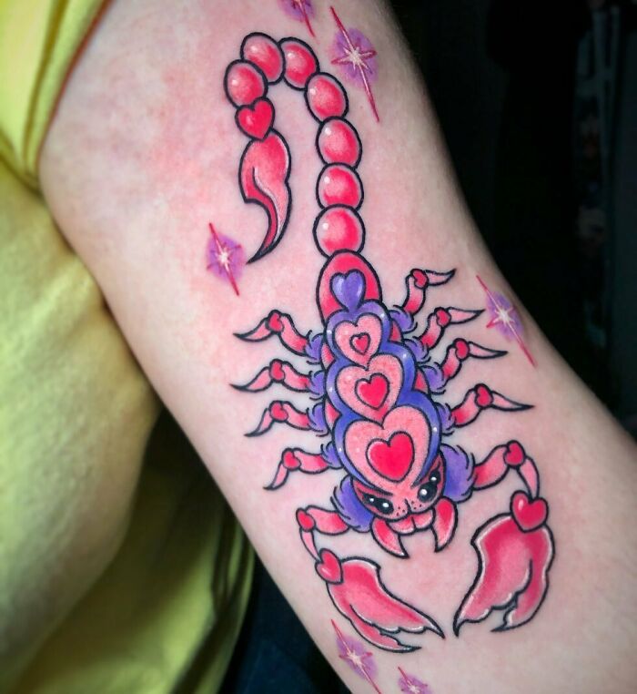 Colorful Scorpio zodiac tattoo featuring a scorpion with heart designs on an arm.