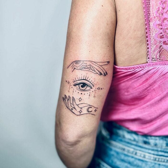 Two hands and the eye in between arm tattoo 