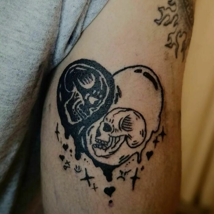 Two skulls in the heart shape tattoo 