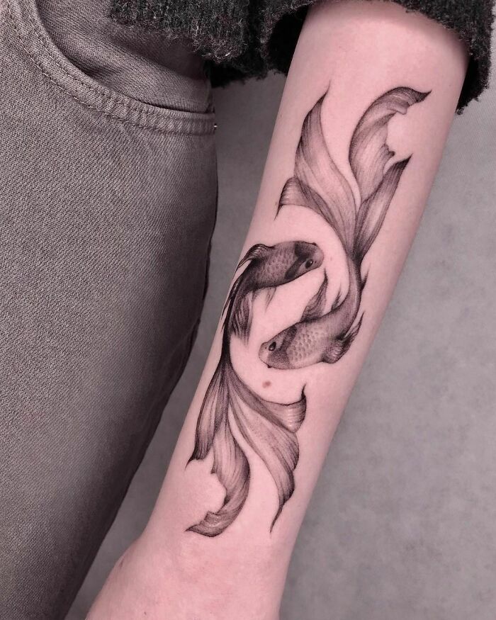 Detailed Pisces zodiac tattoo on a forearm, featuring two intricately designed fish with flowing fins.