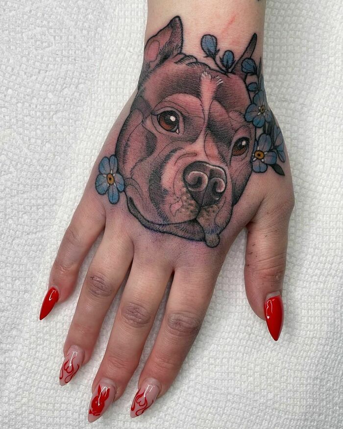 Realistic dog face with blue flowers tattoo on the hand