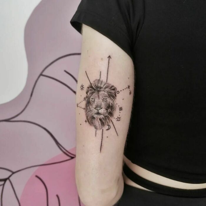 Arm with a detailed lion zodiac tattoo featuring constellation and celestial symbols.