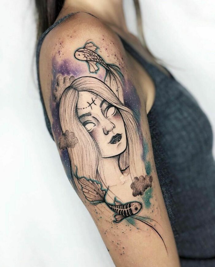 Zodiac tattoo of a woman's face with fish and clouds on upper arm.