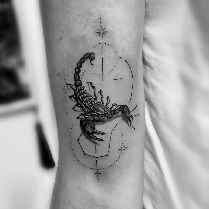 Scorpion zodiac tattoo with geometric details on arm, black ink.