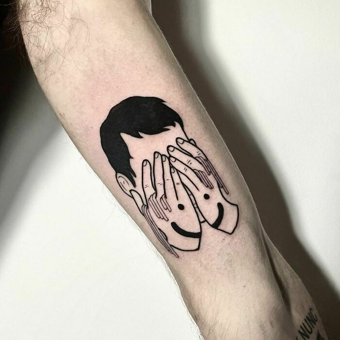 Man covering face with the painted smile on hands tattoo 