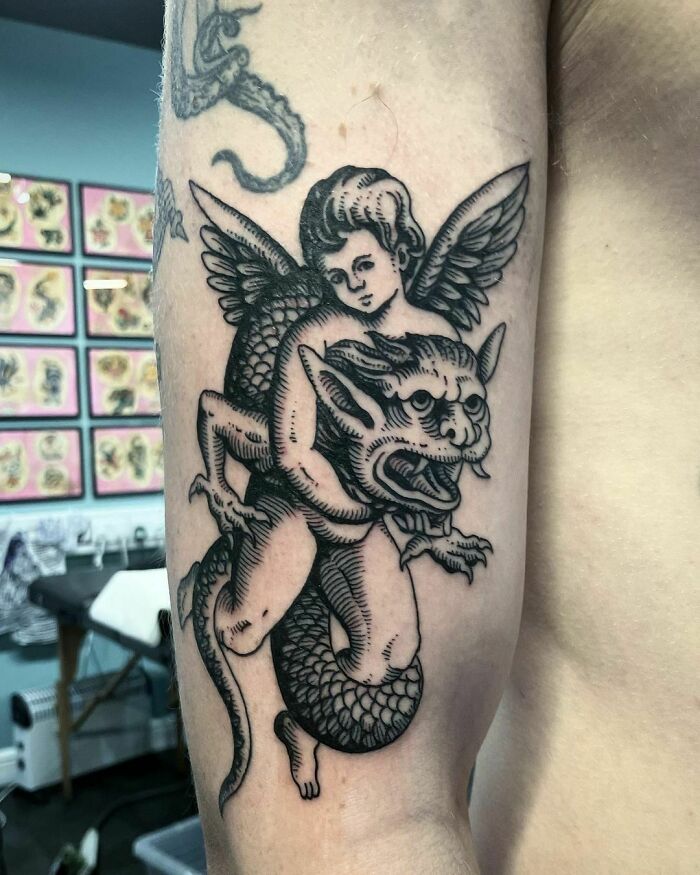 cupid holding a snake demon in a chokehold tattoo