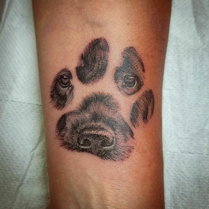 Dog face in a footprint memorial wrist tattoo