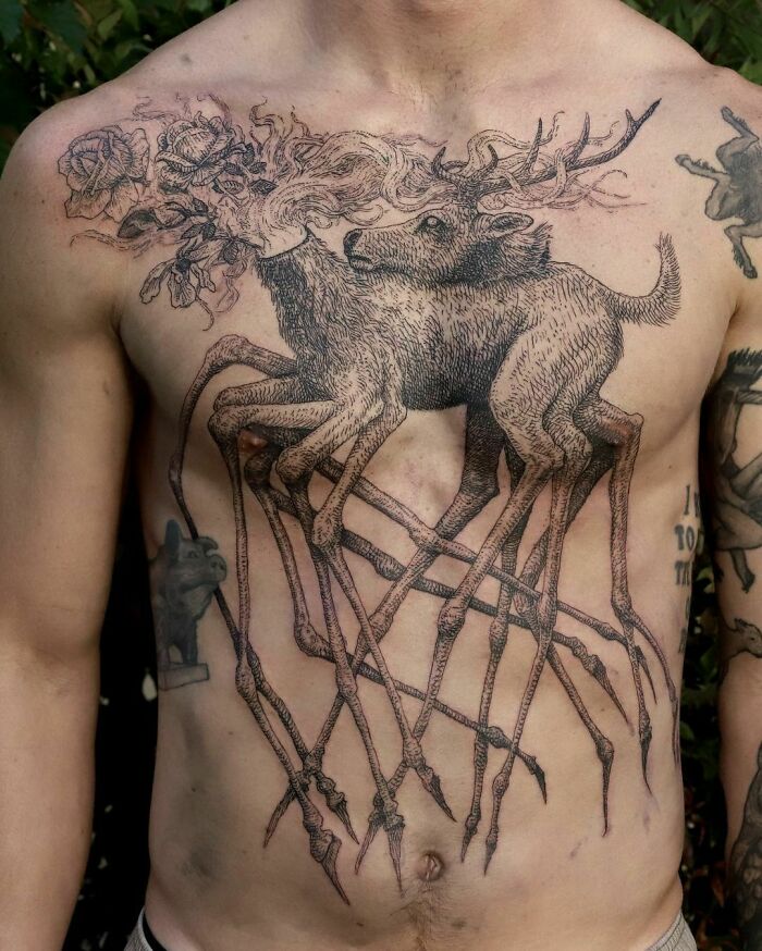 Detailed gothic tattoo of a stag with floral elements on a man's chest.