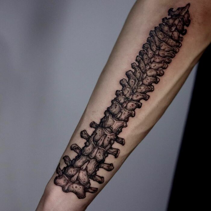 A detailed gothic tattoo of a spine design on a forearm.