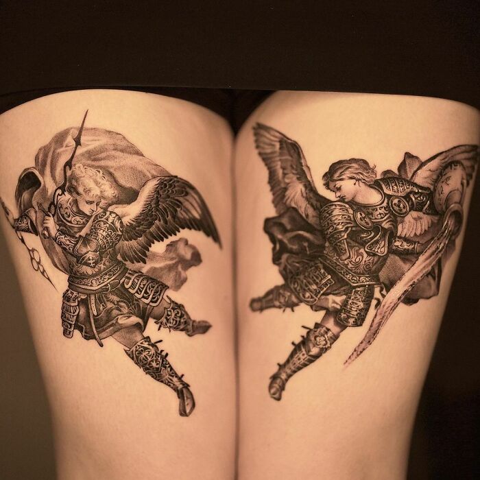 Two detailed gothic tattoos of armoured angels with wings on inner thighs.