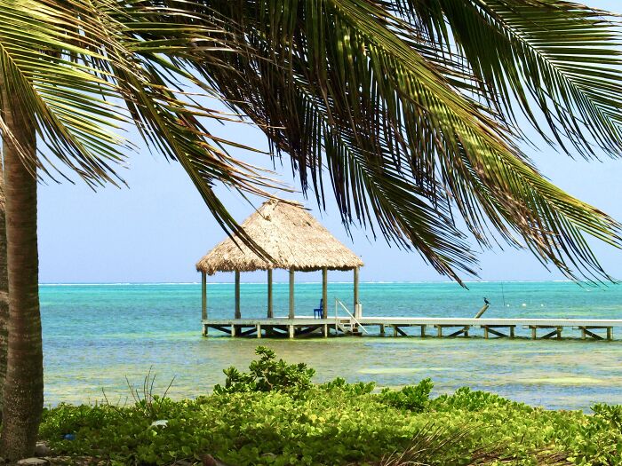 A Dock And Palapa Over Clear Water In San Pedro, Belize
