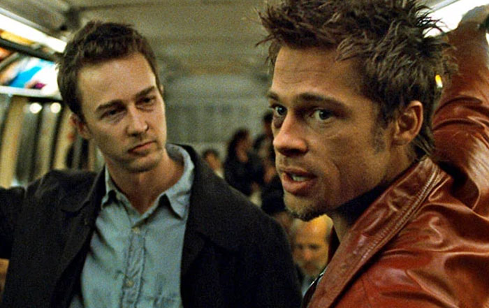 Actors in a tense scene, engaging in conversation on a subway, one wearing a red jacket. Actors in a tense scene, engaging in conversation on a subway, one wearing a red jacket.