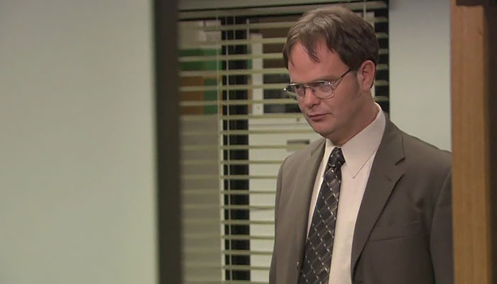 Dwight Schrute looking with a threatening look through a door