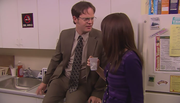 Dwight Schrute sitting on a counter talking to Erin