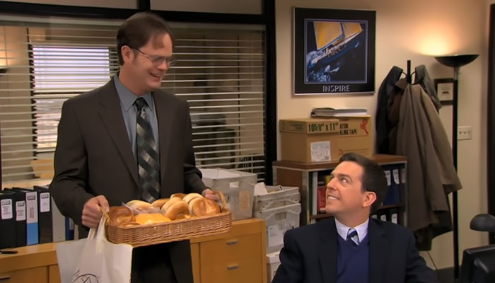 Dwight Schrute happily looking at Andy while holding a tray full of bagels