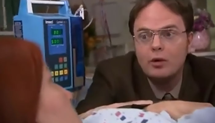 Dwight Schrute looking at Meredith Palmer, who's lying in a hospital bed