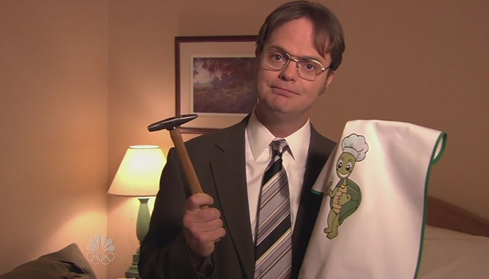 Dwight Schrute holding a hammer and a towel 